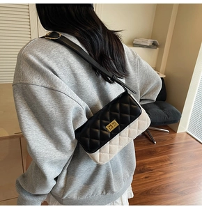 Detail of a quilted contrast crossbody bag with a gold twist-lock on a female model