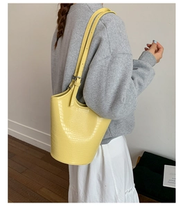 Model wearing bright yellow faux crocodile bucket bag with adjustable shoulder strap
