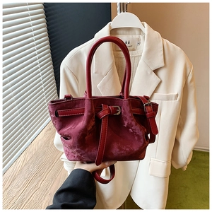 Détail d'un sac à main en velours bordeaux avec boucle réglable et poignées solides