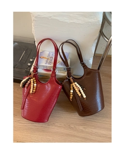 Detailed view of crocodile pattern bucket bags with wooden bead tassels and dual handles