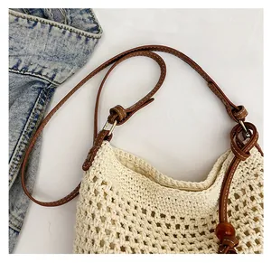 Detail of cream crochet tote bag with brown leather strap and decorative wood beads
