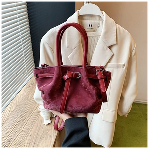 Vue détaillée du sac seau bordeaux en daim avec sangles en cuir et boucles métalliques