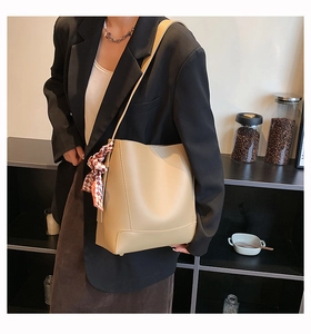 Detail of beige leather tote bag with a decorative red and white checkered scarf