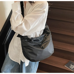 Detail of a black large crescent crossbody bag with double zippers and side branding label