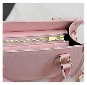 Détail macro du zip doré et de l'anneau en D sur le sac en cuir rose grainé