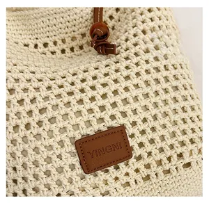 Close-up of woven tote bag texture featuring a leather brand tag and drawstring detail