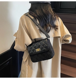 Detail of classic black quilted shoulder bag with gold twist-lock and slim leather strap