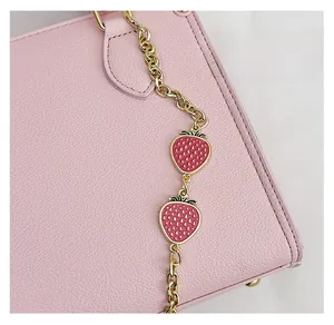 Détail du charm fraise en émail avec chaîne dorée sur un sac à main en cuir rose