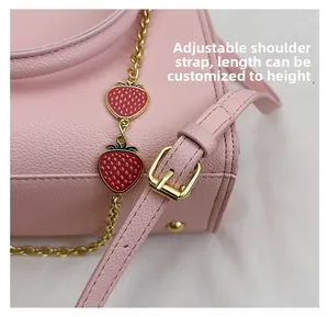 Détail du sac cabas en cuir rose avec pendentifs fraises et bandoulière réglable