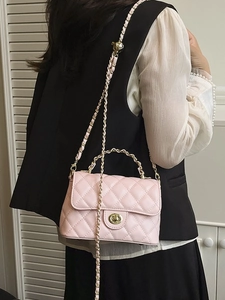 Sac bandoulière matelassé rose clair avec chaîne dorée et fermoir pivotant sur modèle