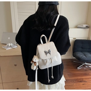 Detailed view of white mini backpack featuring silver butterfly clasp and plush bear charm
