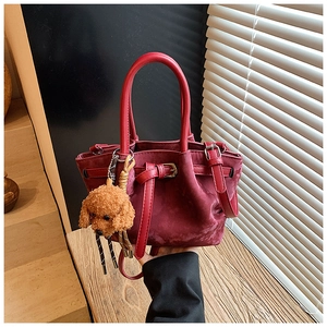 Vue détaillée du sac seau bordeaux en cuir et suède avec un petit pendentif ours en peluche