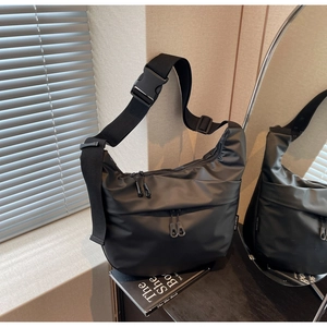 Detail of black waterproof nylon crossbody bag with adjustable buckle strap and zip pockets