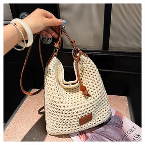 Detail of hand-woven cream tote bag with brown leather strap and brand patch on the side