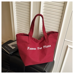 Dettaglio della borsa tote in tela rossa con stampa Famous For Pizza e tracolla larga