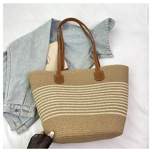 Detail van handgeweven strooien draagtas met lederen hengsels en beige strepen