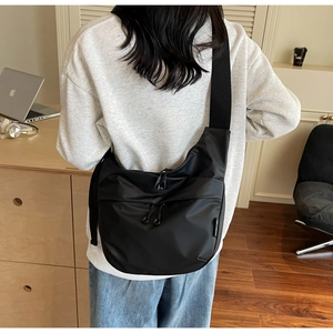 Close-up of black nylon crossbody bag with dual front zippers and wide shoulder strap