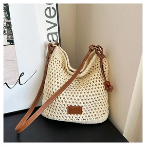 Detailed close-up of beige hollow woven tote bag with leather logo tag and wood bead strap