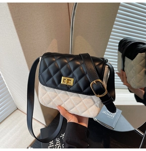 Detail of contrasting black and beige quilted crossbody bag with golden metal twist lock