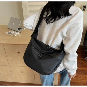Detail view of large black nylon crossbody bag with functional zippers and wide strap
