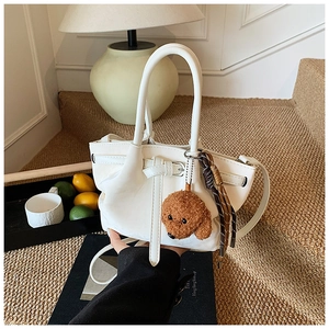 Détail du sac à main blanc en cuir grainé avec un porte-clés peluche ours mignon