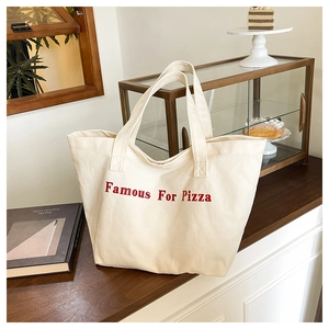 Dettaglio della borsa tote in tela crema con elegante stampa di lettere rosse
