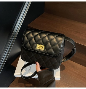 Detail of black quilted shoulder bag with matte leather finish and gold metal turn-lock
