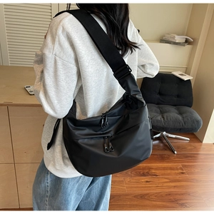 Detail of black large capacity crossbody bag with double front zippers and wide strap