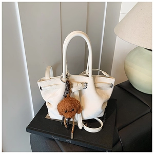 Détail du sac seau en cuir crème avec cordon et breloque ours en peluche mignon