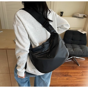 Detail view of large black waterproof nylon crossbody dumpling bag with wide strap
