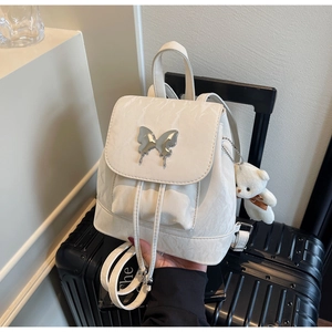 Detail of cream backpack with marble texture, metal butterfly clasp and teddy bear charm