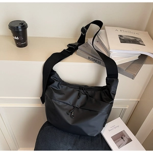 Detail of black nylon crescent bag featuring functional dual front zippers and wide strap