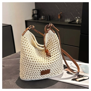 Detail of hand-woven cream tote bag with hollow grid texture and brown leather straps