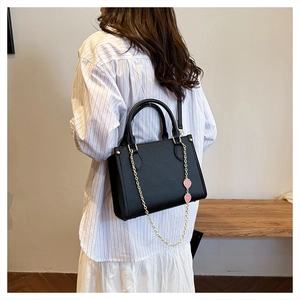 Détail du sac cabas en cuir noir avec chaîne dorée et breloques de fraises