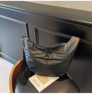 Close-up of waterproof black crossbody bag with pleats and zip pockets on a seat