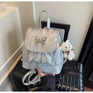 Detail of silver metallic backpack with butterfly buckle and cute teddy bear charm