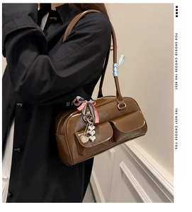 Detail of a brown glossy bowling bag with front pockets and heart-shaped charm accessory