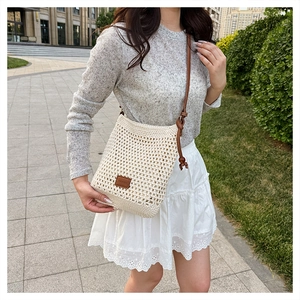 Detail of beige hollow crochet tote bag with brown leather strap for summer beach vacation