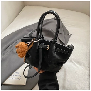 Détail du sac cabas en daim noir avec boucle décorative et charmant pendentif ours en peluche