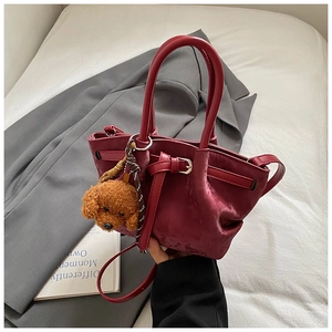 Détail du sac seau en velours bordeaux avec boucle décorative et breloque peluche chien