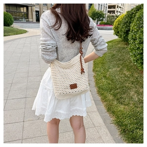Detail of hollow woven beach tote with brown leather strap and wooden bead accents