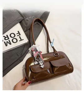Close-up of brown patent leather shoulder bag with front pockets and decorative charms