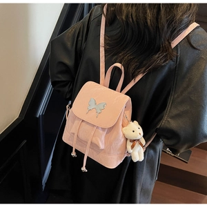 Detail of pink PU leather backpack with silver butterfly and plush bear charm