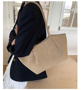 Détail du sac cabas beige avec nœud latéral et texture en daim porté par un mannequin