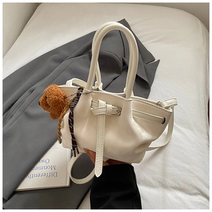 Détail du sac à main trapèze en cuir PU blanc avec double poignée et charm ours en peluche