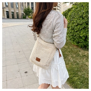 Detail of hollow woven beach tote bag with brown leather label and adjustable rope strap