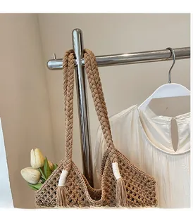 Detail of woven straw tote bag featuring thick braided handles and bohemian tassels