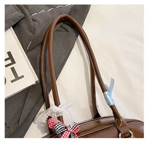 Detail of dark brown leather bowling bag featuring decorative lace and ribbon bows
