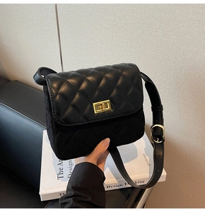Detail of black quilted crossbody bag with gold metal turn-lock and mixed leather textures