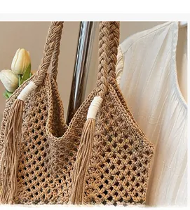 Detailed macro view of handmade mesh straw bag featuring thick braided straps and long tassels